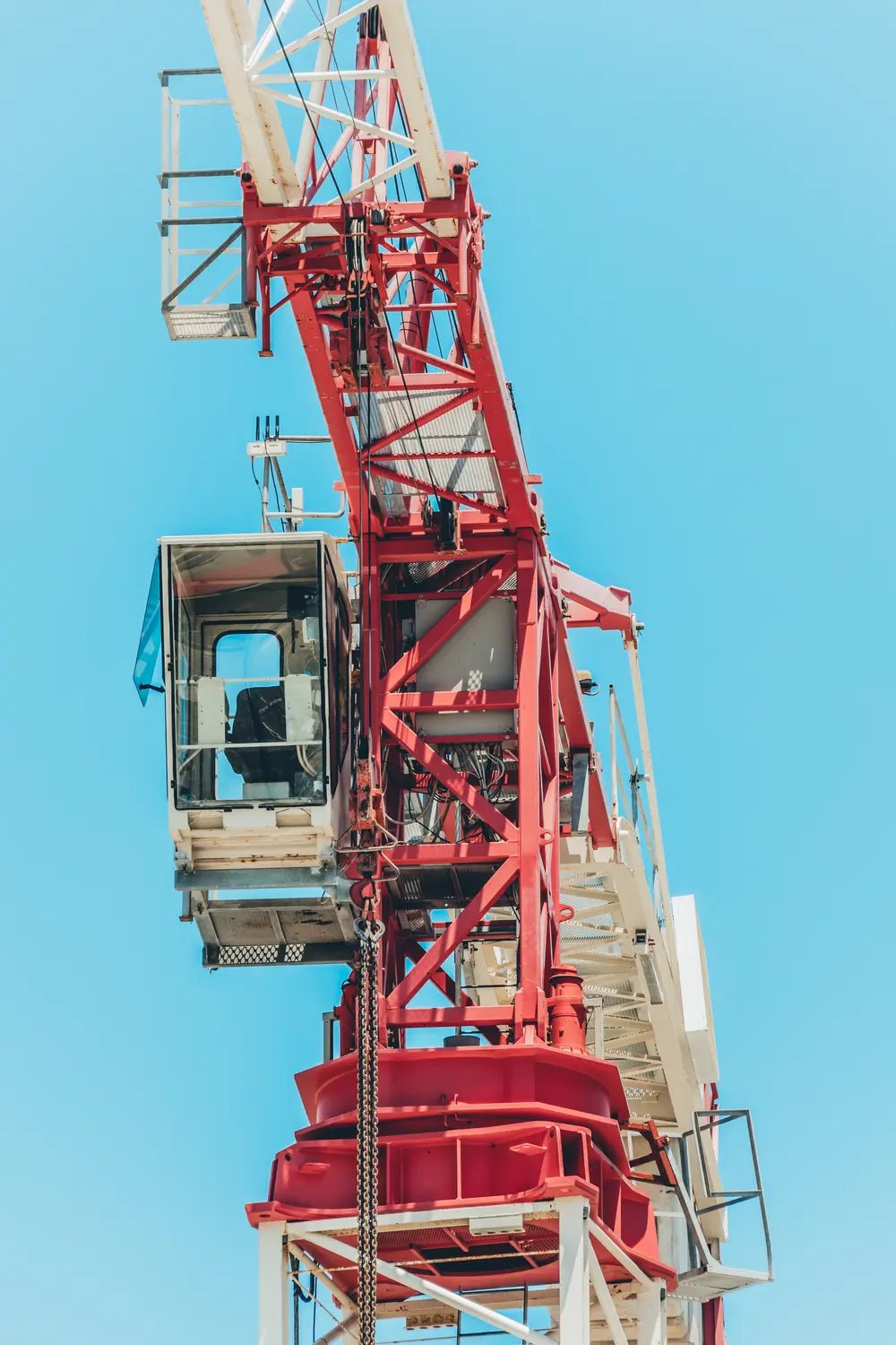 Grua-torre vermelha e branca erguida contra o céu limpo