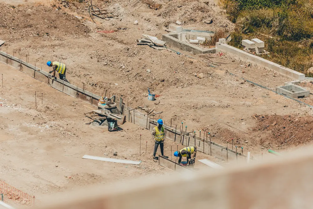 Trabalhadores no terreno escavado, junto às cofragens