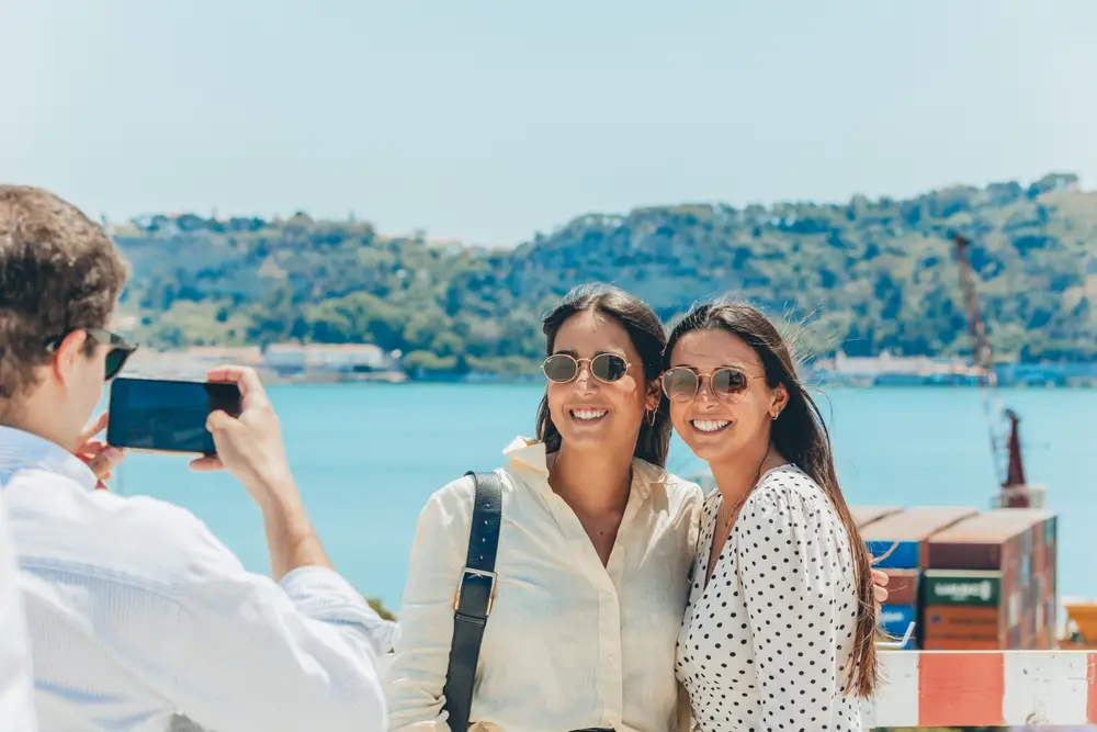 Duas mulheres a posar para uma fotografia junto ao rio