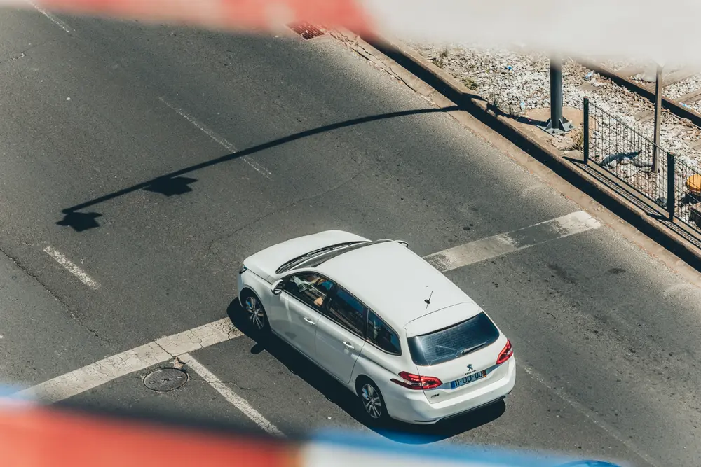 Vista aérea de um carro branco na estrada, ao lado da linha férrea