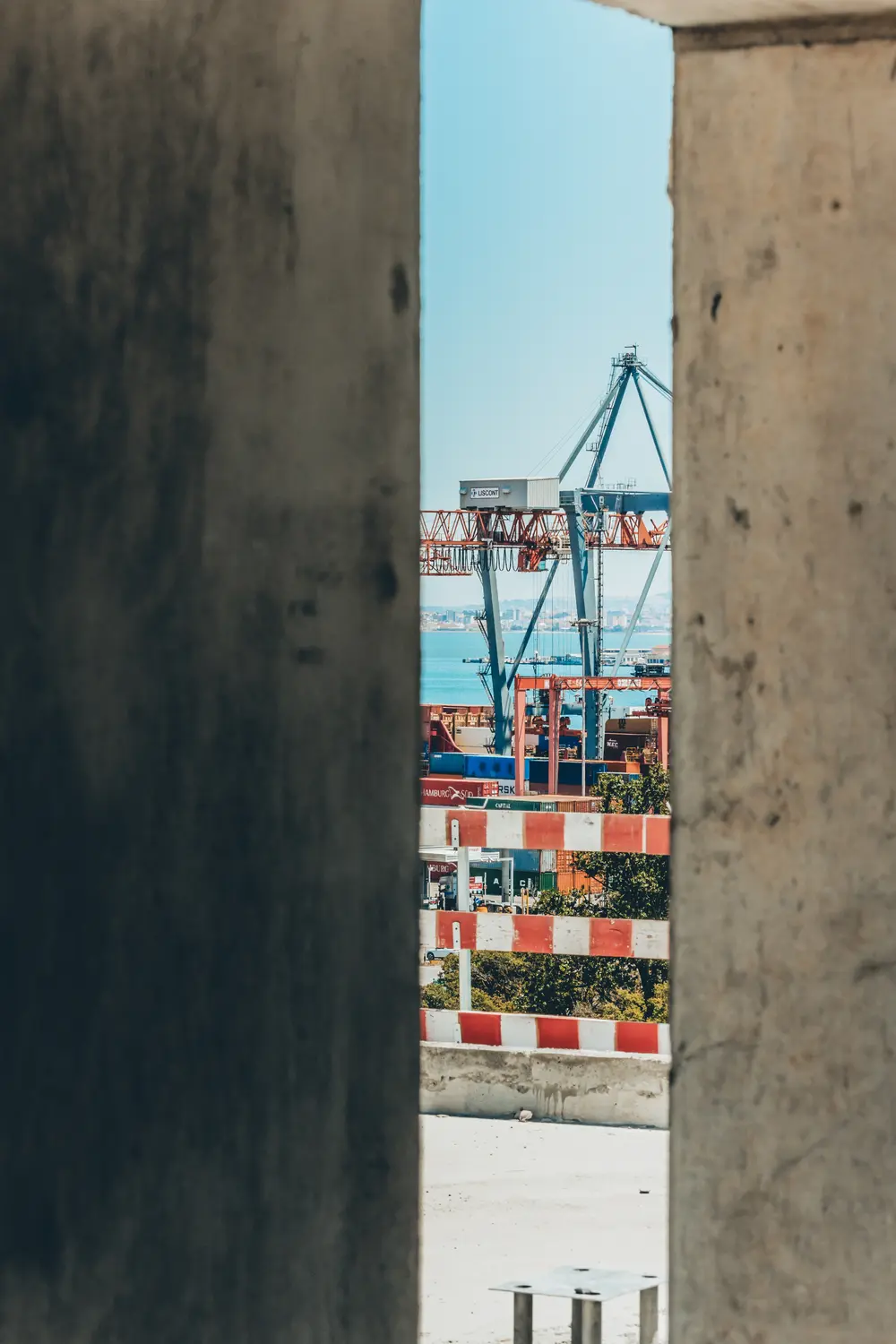 Gruas do porto de Lisboa vistas pela fresta entre dois pilares de betão