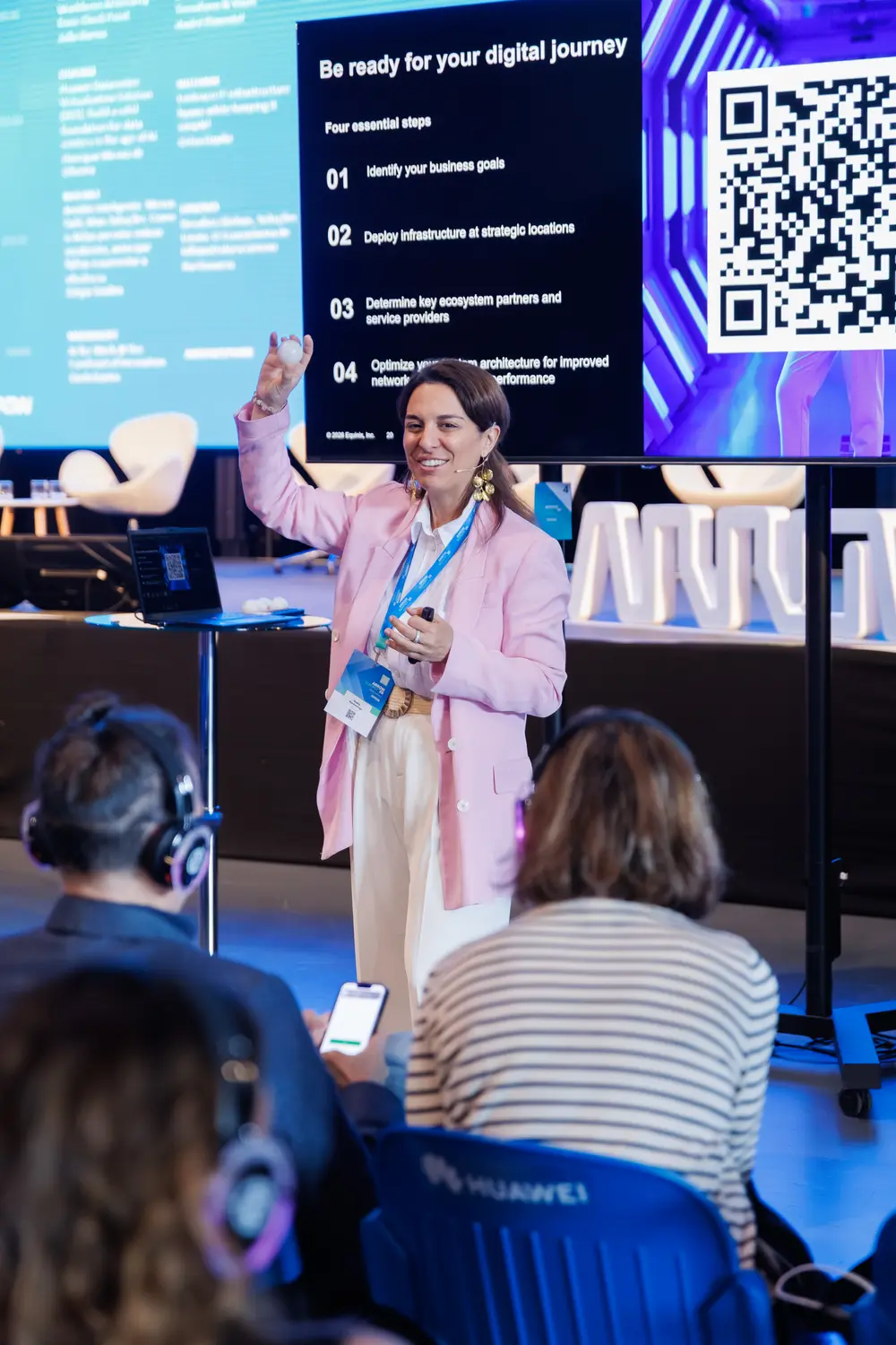 Oradora a apresentar, com um código QR projetado no ecrã