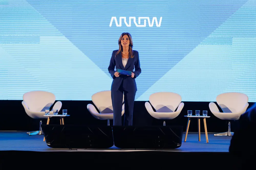 Apresentadora em palco, com marca no ecrã