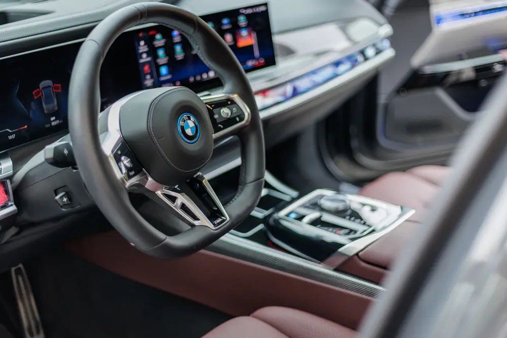 Volante e painel digital do BMW, com interior em pele bordô