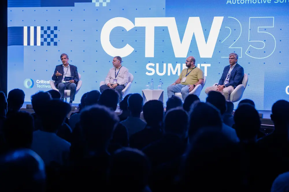 Painel de debate em palco, com a plateia em primeiro plano