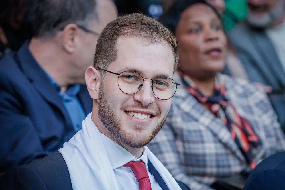 Graduado a sorrir na bancada, com o cachecol da academia