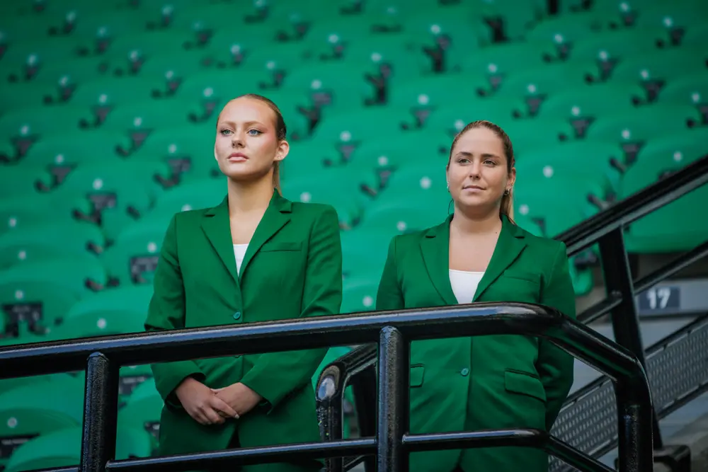 Duas promotoras de verde na bancada do estádio