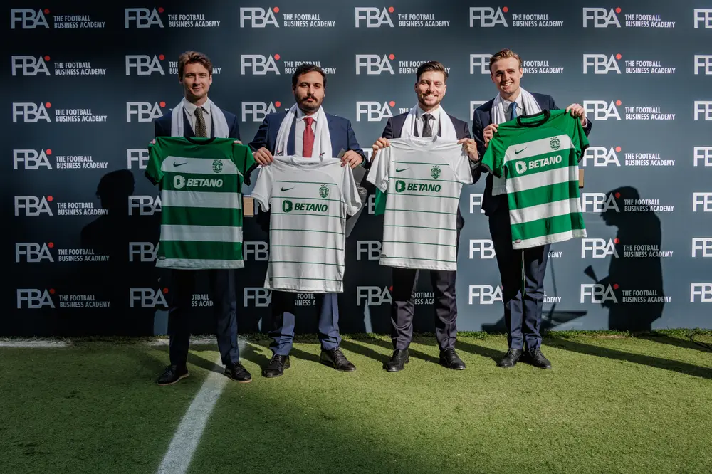 Quatro graduados com as camisolas do clube, diante do painel de marca
