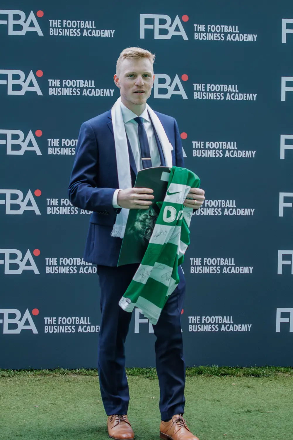 Graduado com a camisola do clube, diante do painel da academia
