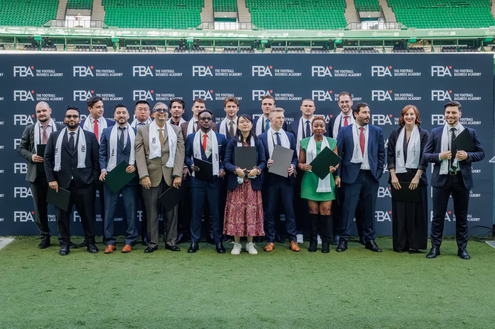 Fotografia de grupo dos graduados diante do painel de marca
