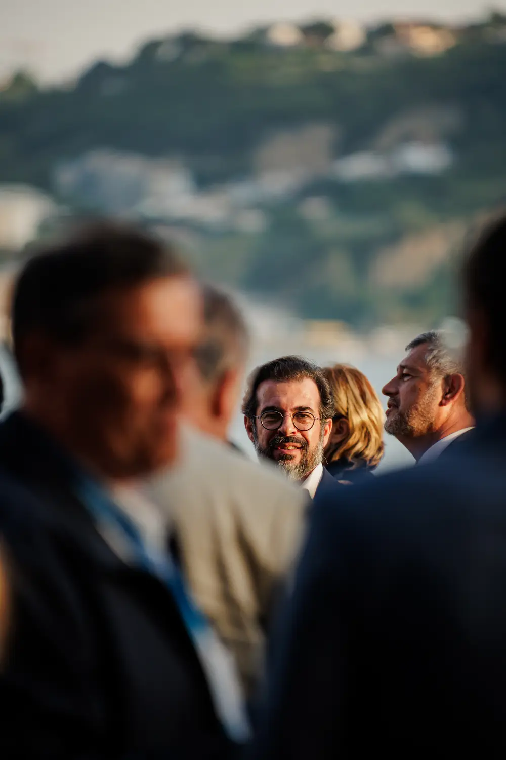 Conversa entre convidados, com o rio desfocado atrás