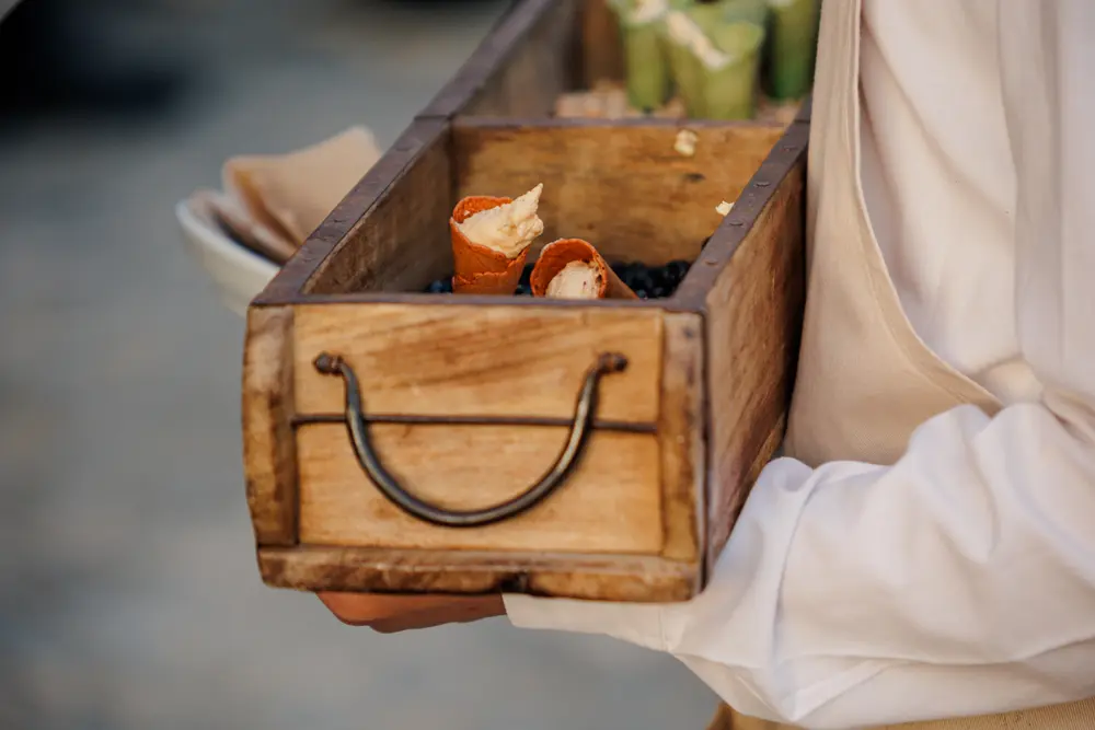 Empregado a servir aperitivos numa caixa de madeira