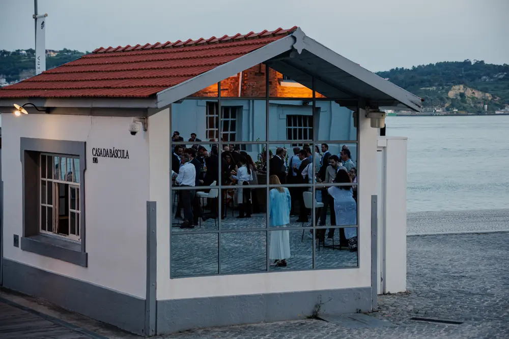 Pavilhão espelhado no cais, a refletir os convidados e o rio