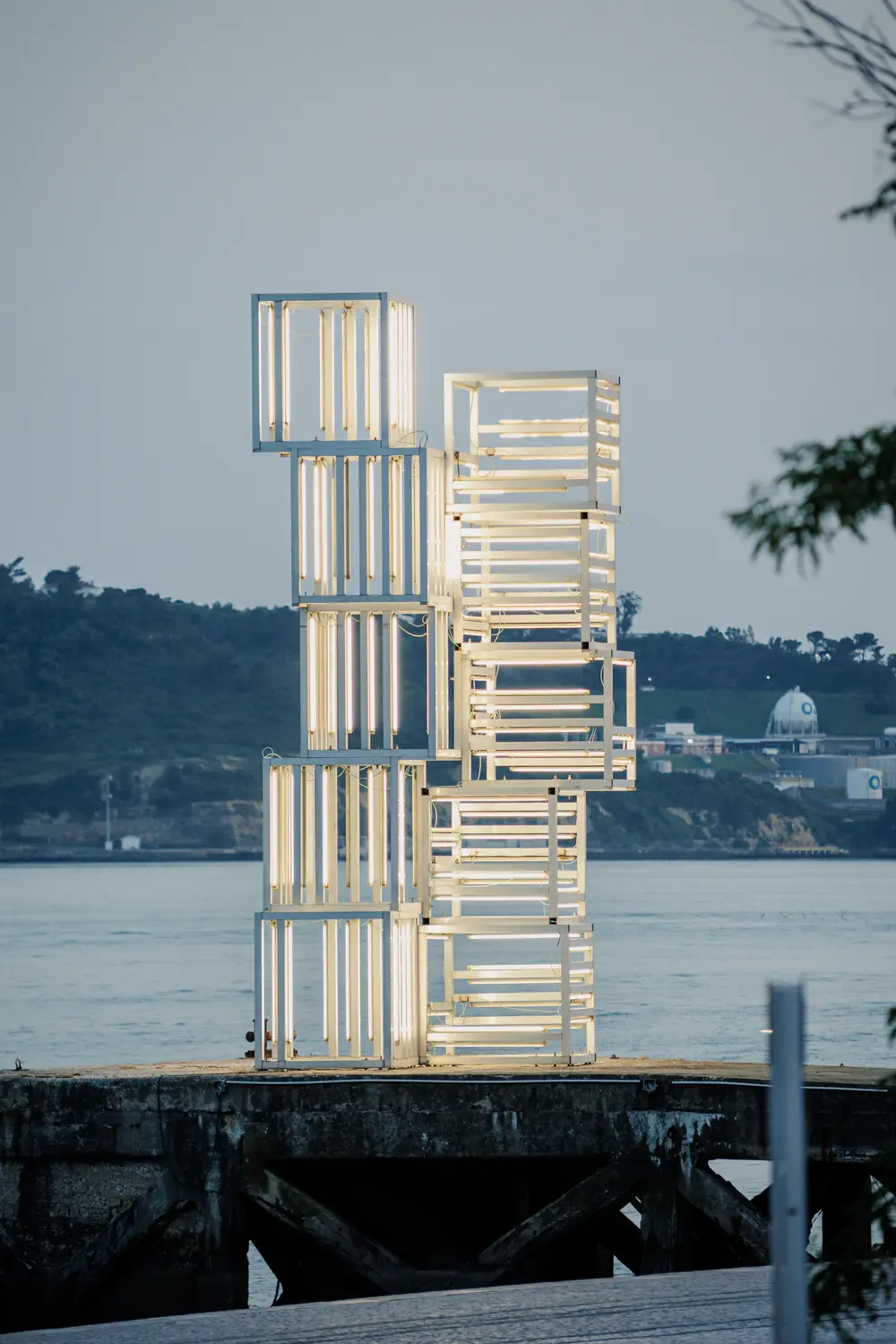 Escultura contemporânea no cais, contra o rio ao anoitecer