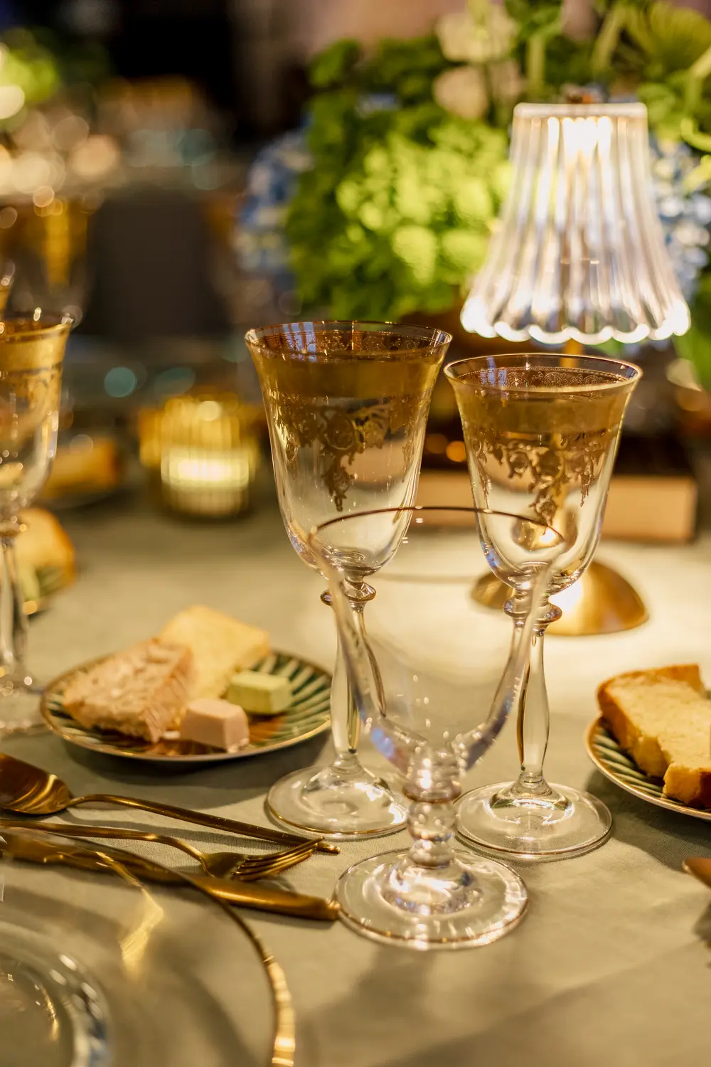 Mesa de jantar posta, com cristais e um candeeiro de mesa
