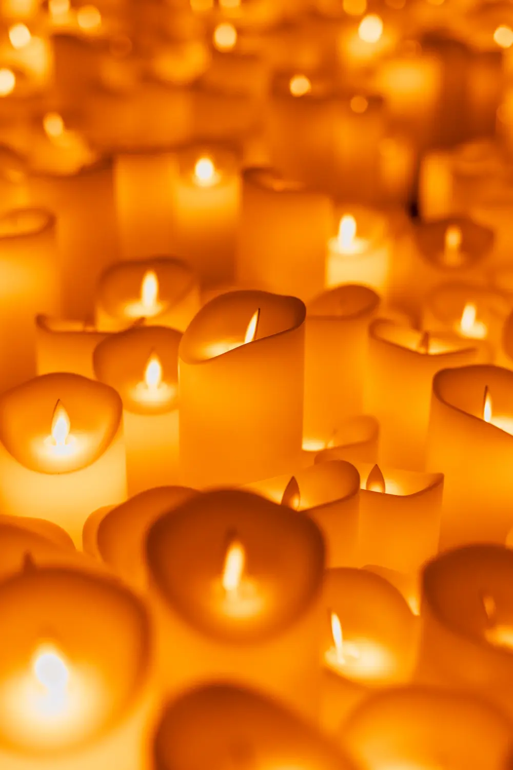Velas acesas em primeiro plano, com pouca profundidade de campo