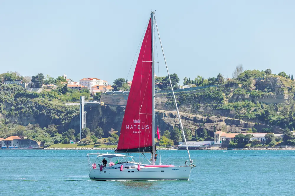 Veleiro ao largo, com a margem sul do Tejo em fundo