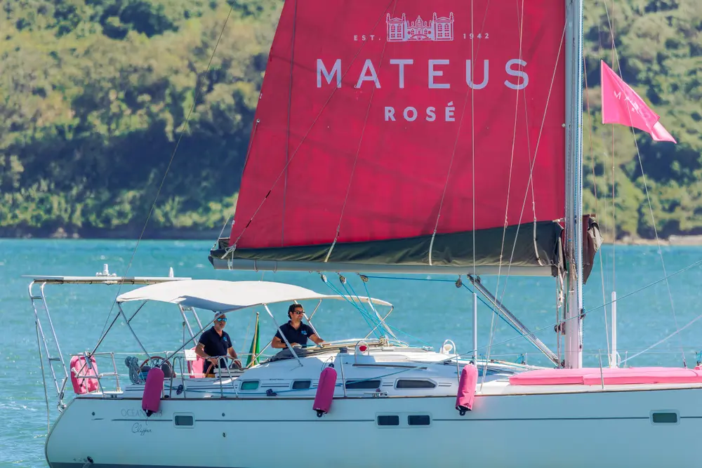 Tripulação no convés sob a vela de marca, com o galhardete ao vento