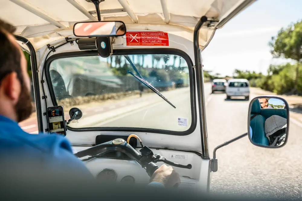 Condutor do tuk-tuk ao volante, na estrada do Guincho, em Cascais