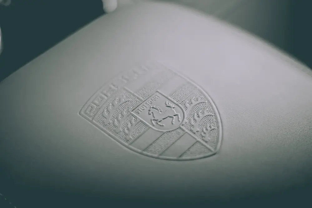 Emblema Porsche em relevo na carroçaria, em luz suave