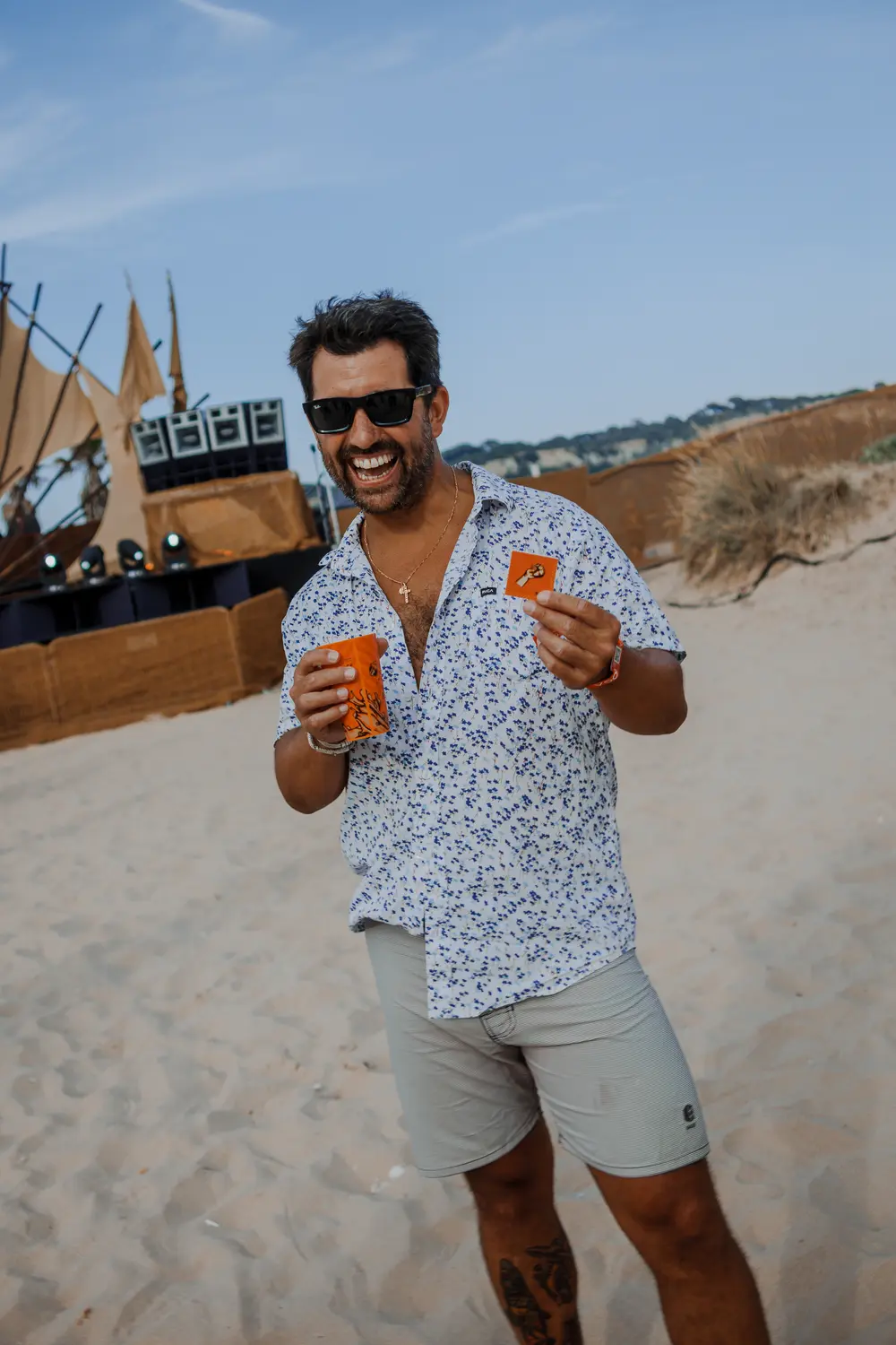 Festivaleiro a brindar com dois copos, na areia