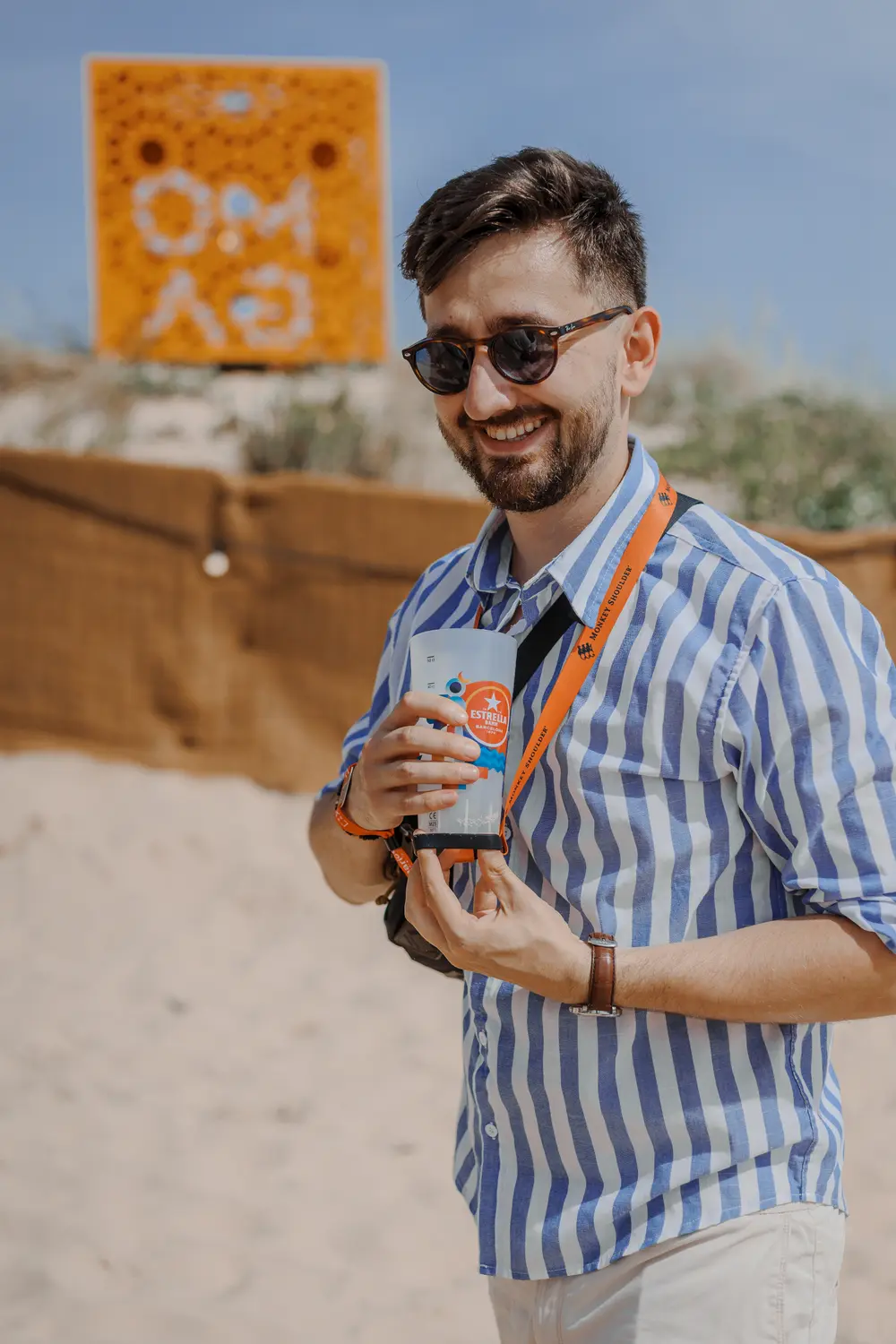 Festivaleiro com bebida na mão, junto à instalação de marca