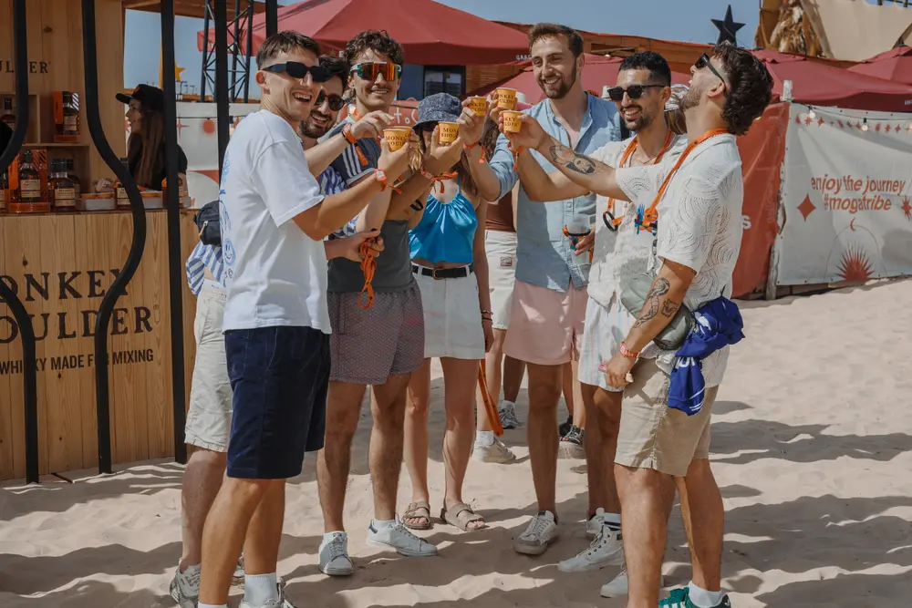 Grupo de festivaleiros a brindar em frente ao bar de marca