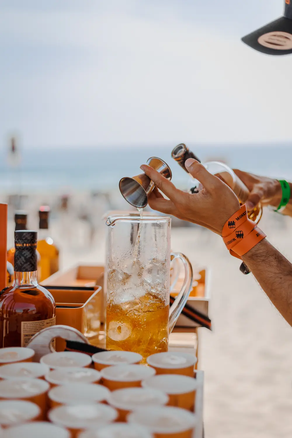 Mãos a servir bebida no balcão do bar da praia