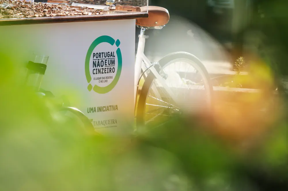 Bicicleta de carga vista por entre a folhagem do jardim