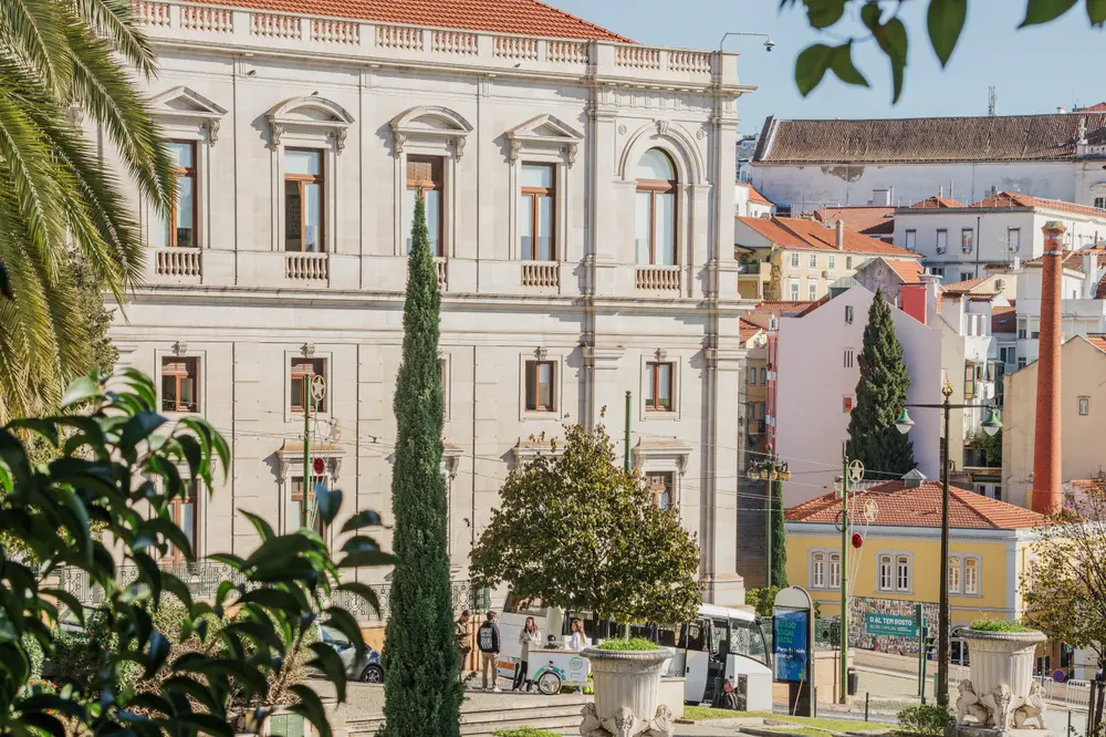 Plano aberto da Assembleia da República por entre as árvores do jardim