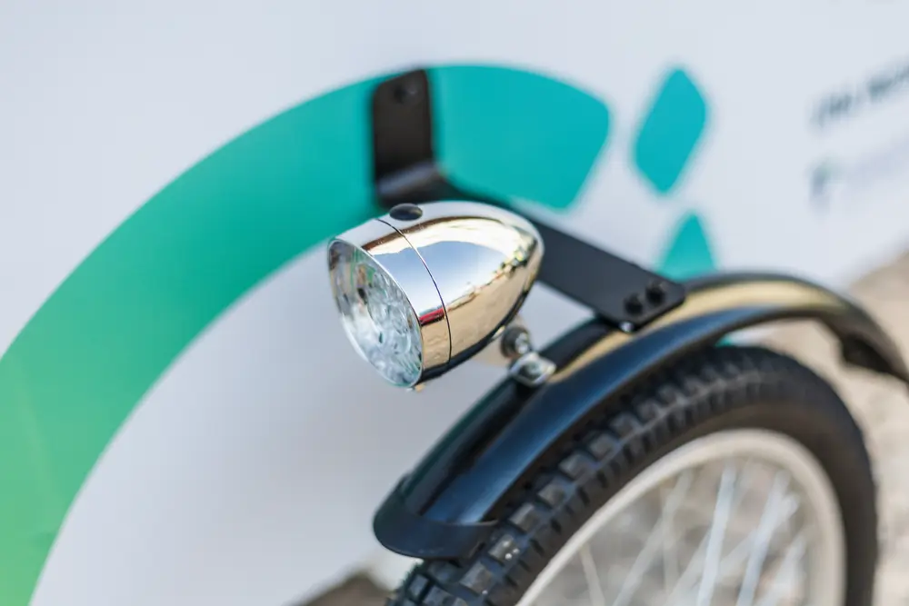 Farol cromado e roda dianteira da bicicleta, contra o painel de marca