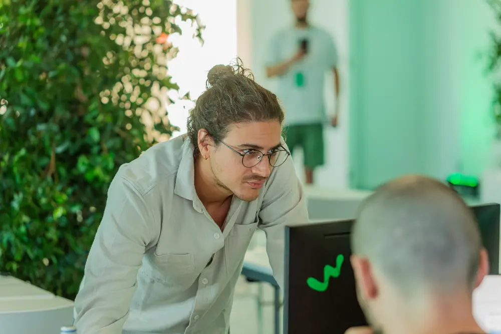 Participante debruçada sobre a mesa a explicar a um colega