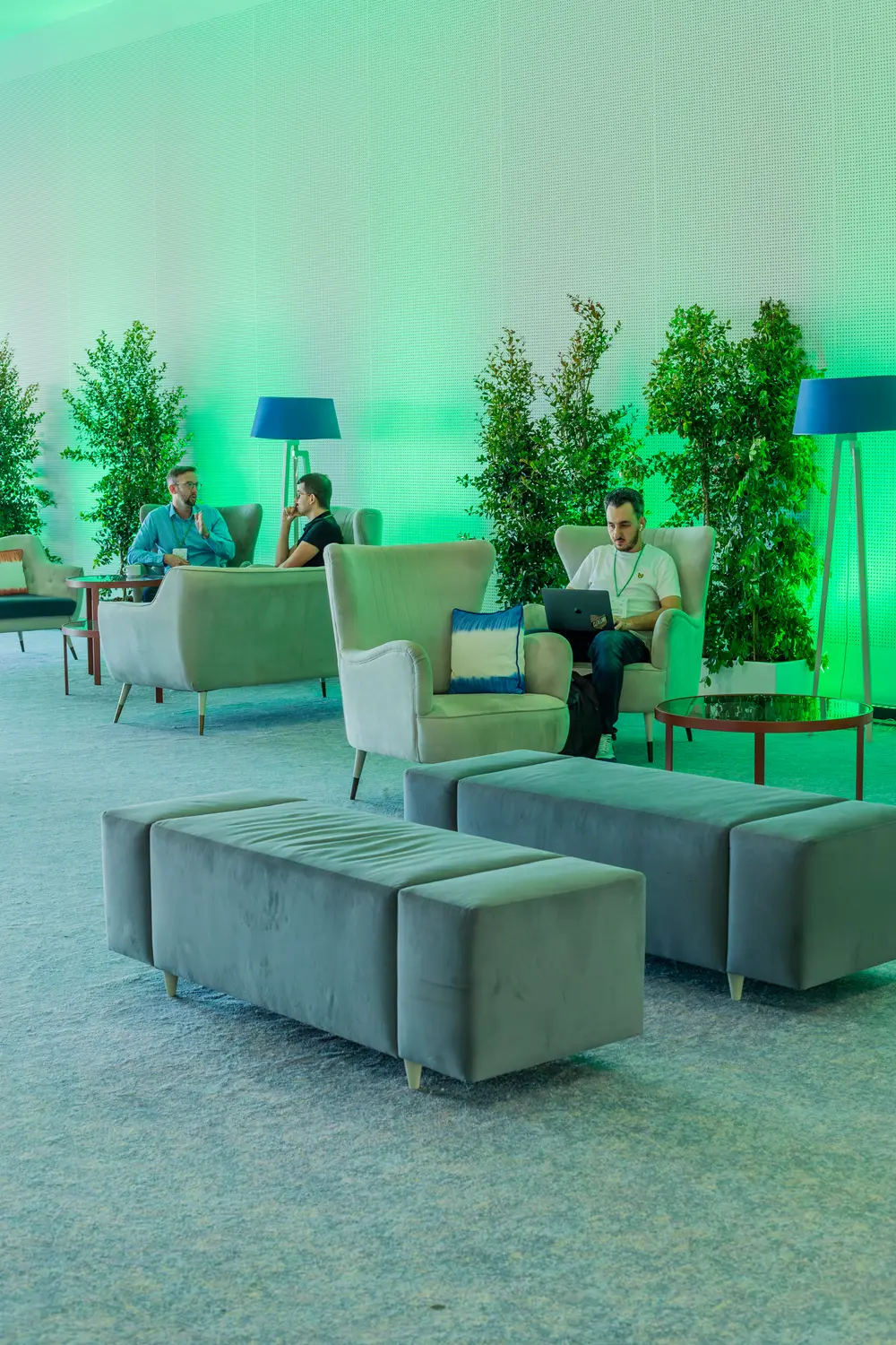 Zona de lounge com poltronas e vegetação, em luz verde