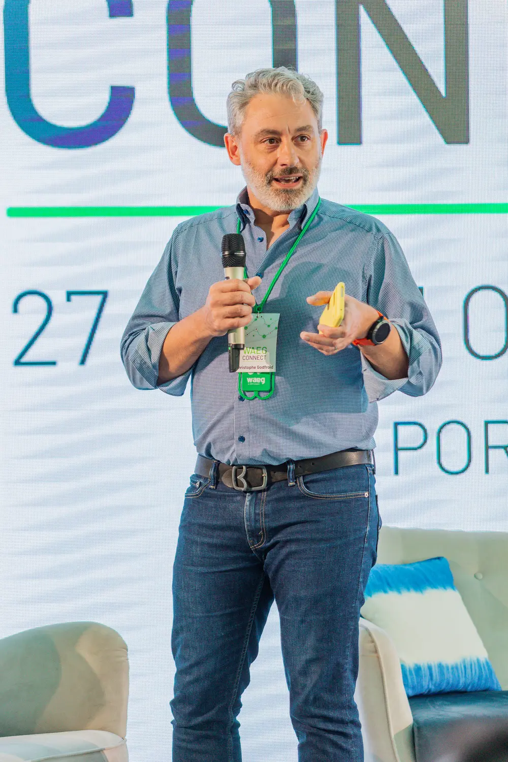 Orador em palco com um objeto na mão, durante a apresentação